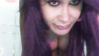 Lusty tranny with purple hairs slowly gets naked on the camera